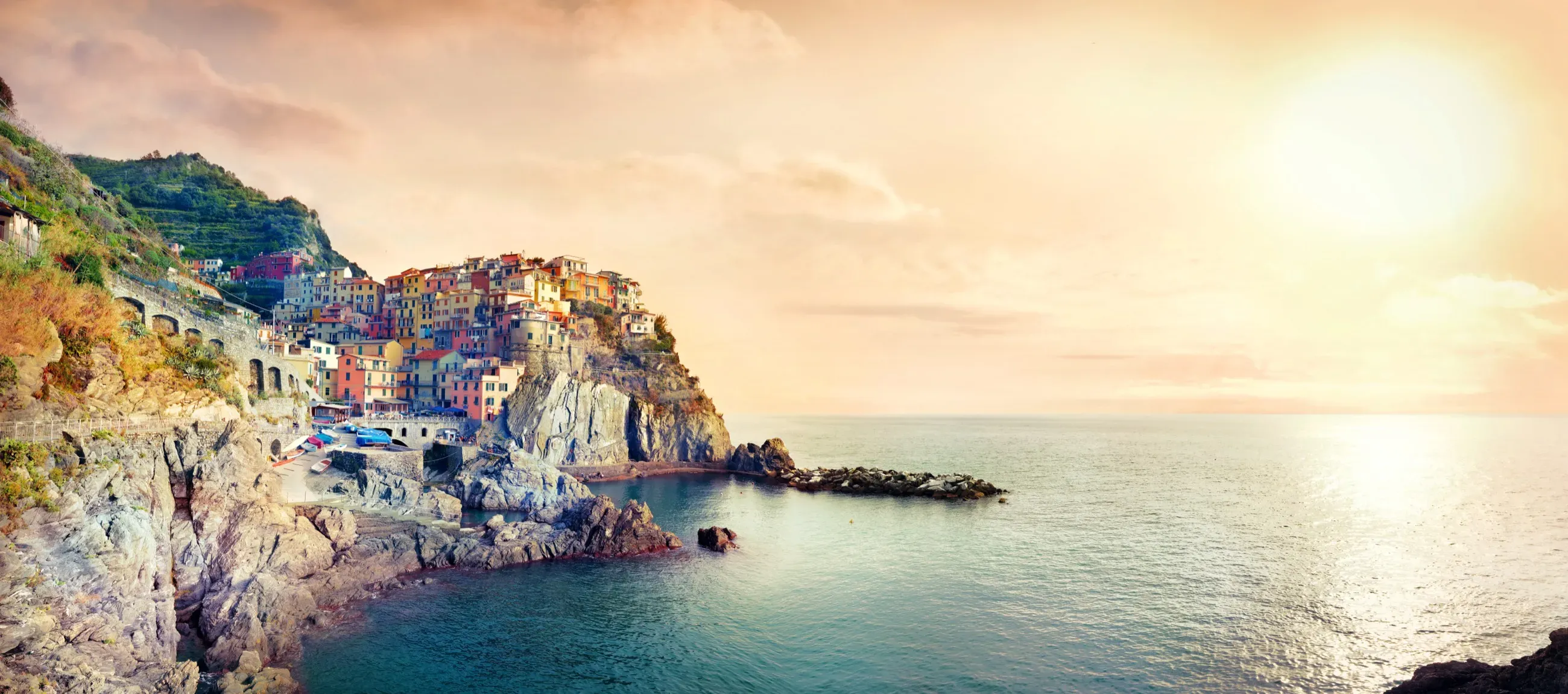 Manarola, a cliffside village of colorful houses above the sea at sunset, Cinque Terre, Italy